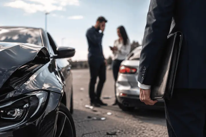 Lawyer holding a folder near two drivers standing by their damaged cars on a road